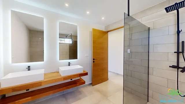 Bathroom with double vanity and walk-in shower at Plumbago Residences
