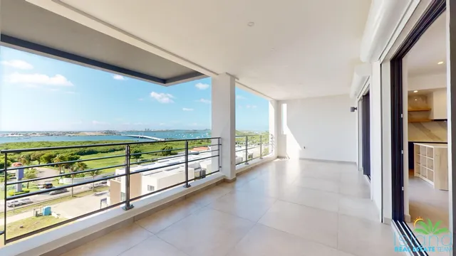 Covered terrace with a wide view over the green hillside below Plumbago Residences
